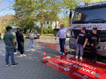 Schüler*innen sitzen im LKW oder stehen vor dem LKW, um den Sichtbereich eines LKW Fahrers kennenzulernen