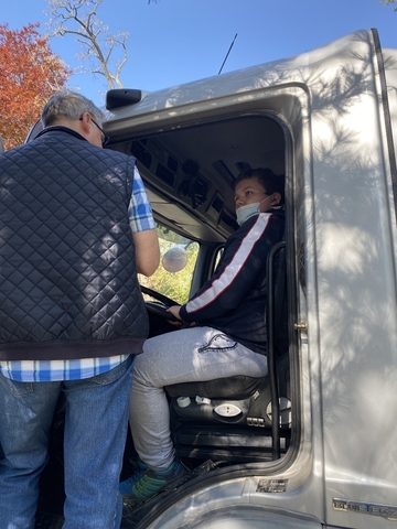 Schüler*innen sitzen im LKW oder stehen vor dem LKW, um den Sichtbereich eines LKW Fahrers kennenzulernen