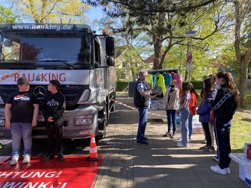 Schüler*innen sitzen im LKW oder stehen vor dem LKW, um den Sichtbereich eines LKW Fahrers kennenzulernen