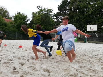 Die Schüler und Schülerinnen machen den Beachplatz sauber und spielen Sportspiele