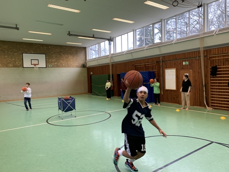 Die Schüler und Schülerinnen spielen Basketball.