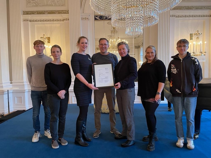 Auf dem Gruppenbild überreicht Frau Briesner (3. von links) die symbolische Eintrittskarte an Frau van Lohuizen, Direktorin des Landesbildungszentrums (3. von rechts).