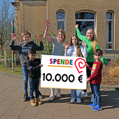 Schüler*innen halten ein Plakat mit der Summe der erlaufenen Spendengelder hoch